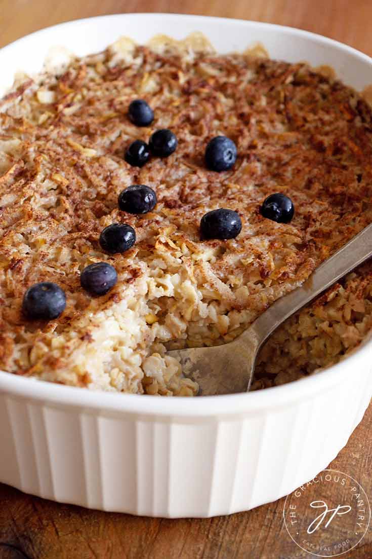 A casserole dish sits with one serving of this baked oatmeal out of the dish.