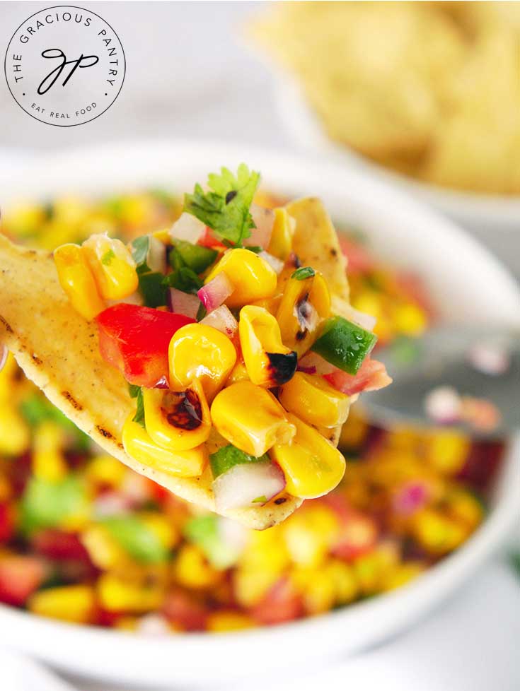 A close up view of a chip holding some of this corn salsa.