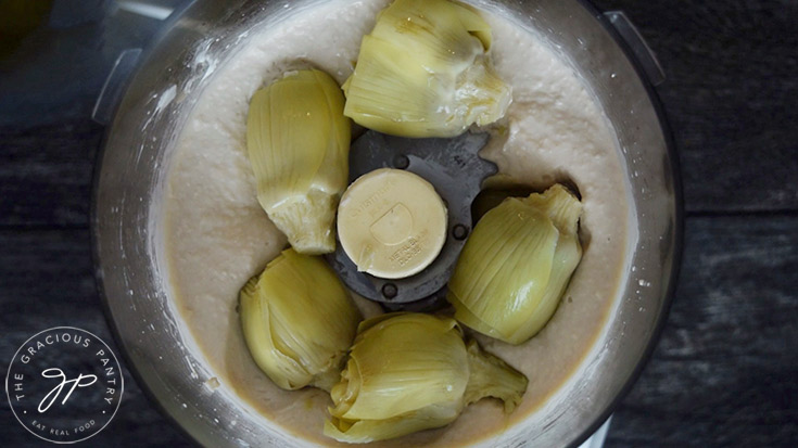 Adding the artichoke hearts to the food processor.