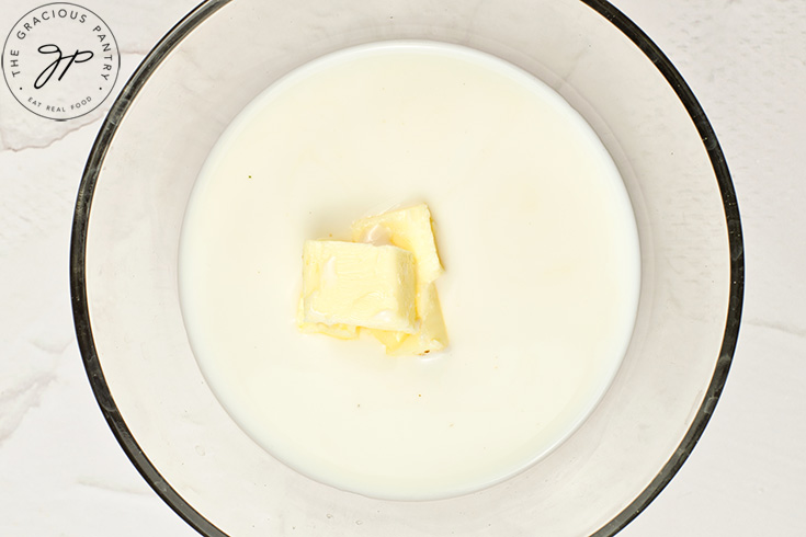 A few pats of butter sitting in a bowl of milk.