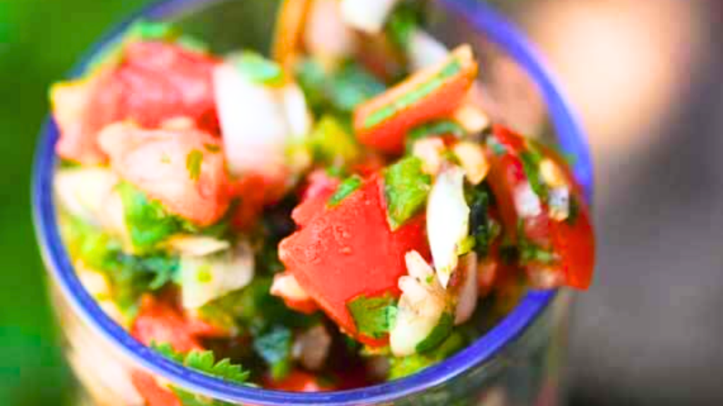 A closeup of a glass filled with cilantro salsa.
