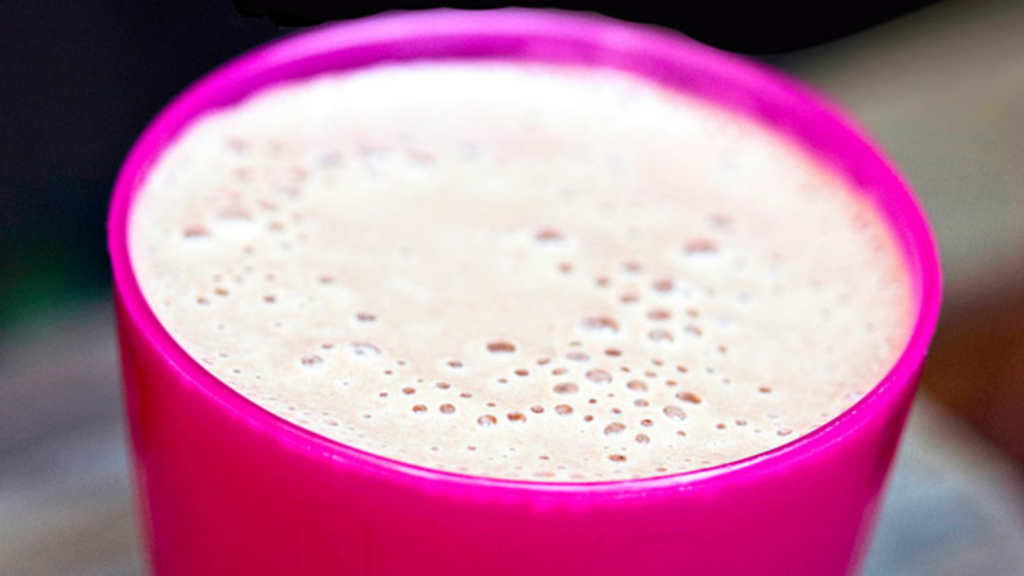 A pink cup filled with chocolate milkshake.