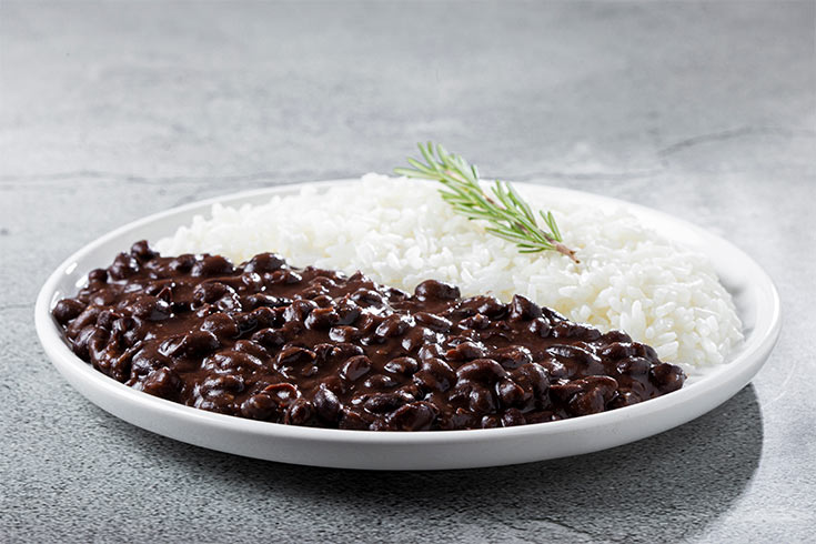 A white plate with white rice and black beans.