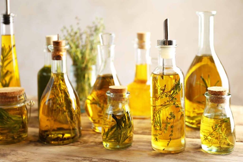 Various glass bottles on a countertop, filled with oils and herbs.