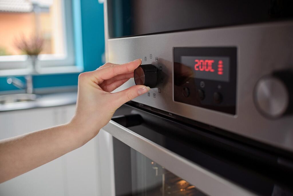 A hand sets the temperature on an oven.