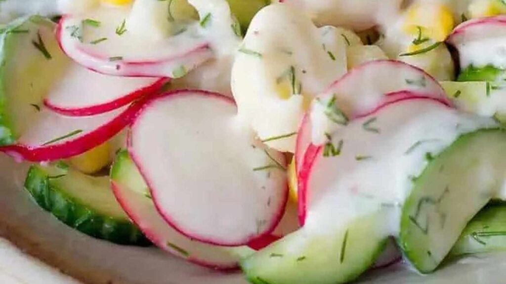 A closeup of creamy vegan cauliflower salad with radishes in a white bowl
