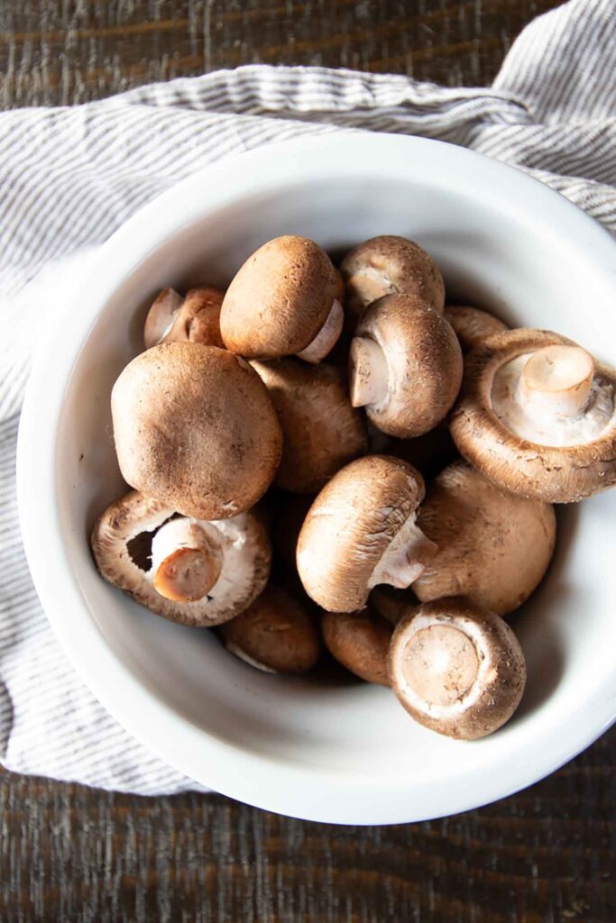 Fresh baby bella mushrooms in a white bowl.