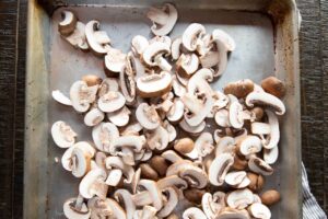 Raw, sliced mushrooms on a sheetpan.