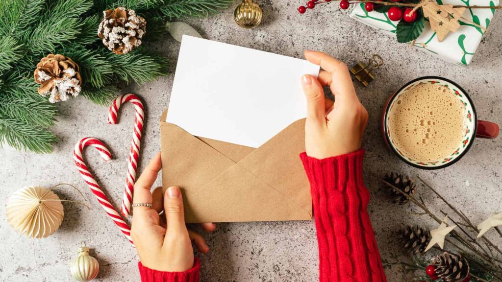 Female hands slide a holiday card into an envelope.