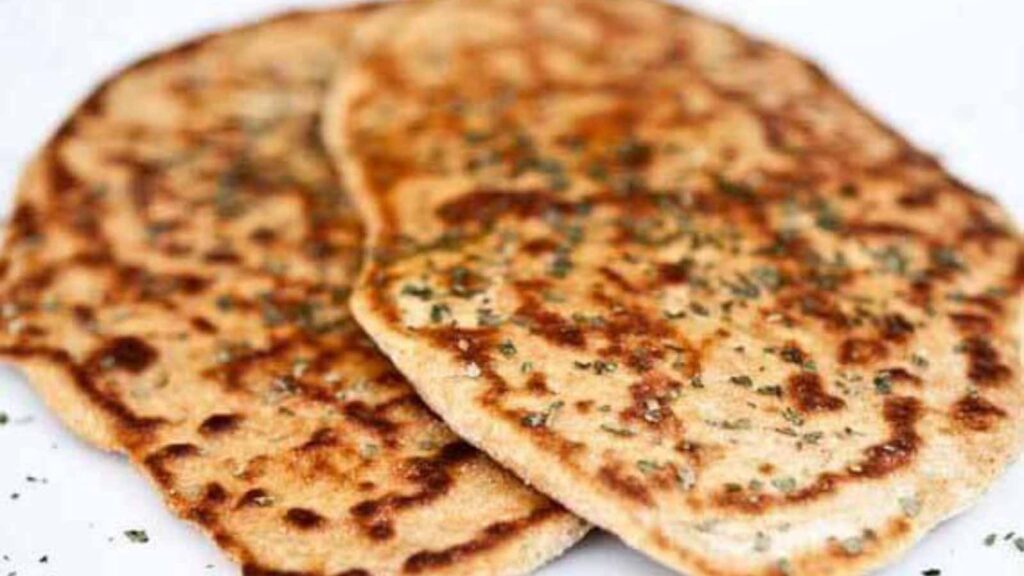Two whole wheat naan on a white surface.