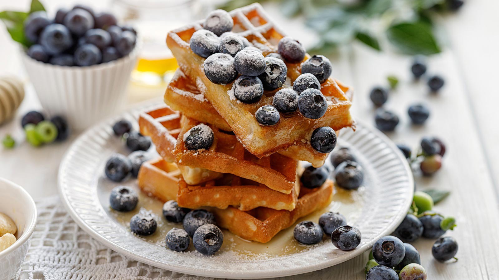 Blueberry Waffles with addition of fresh blueberries sprinkled with castor sugar on a white plate