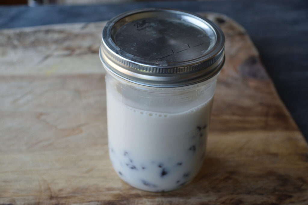 Homemade condensed milk thickening in a canning jar with a lid on.