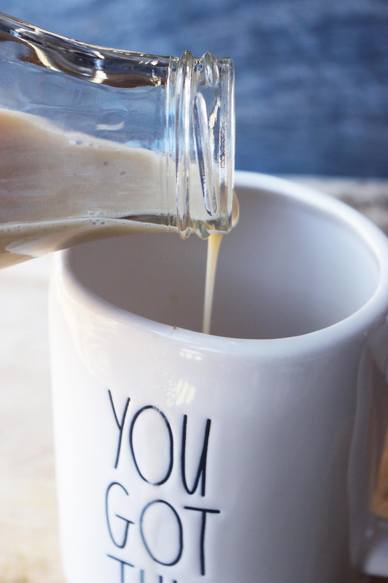 A glass bottle pouring Condensed Milk into a mug.