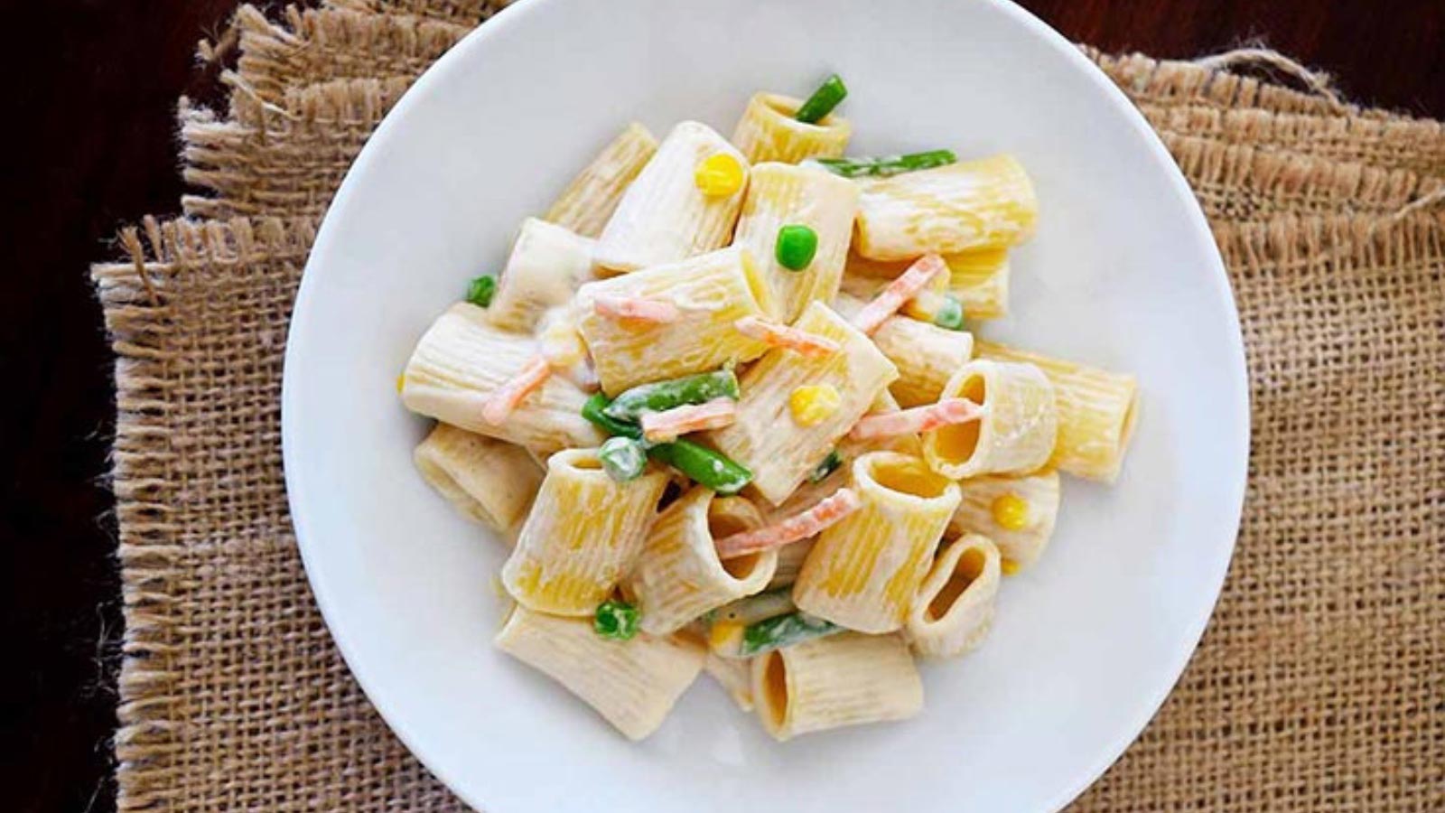 A white plate filled with creamy vegetable pasta.
