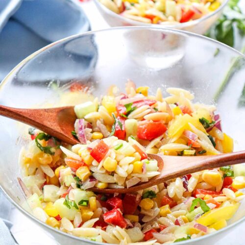 Two glass bowls filled with Rainbow Orzo Salad on a white tabletop.