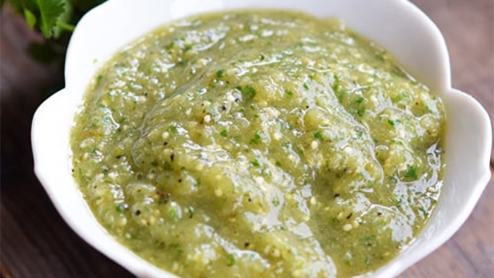 A white, fluted bowl filled with Homemade Salsa Verde.