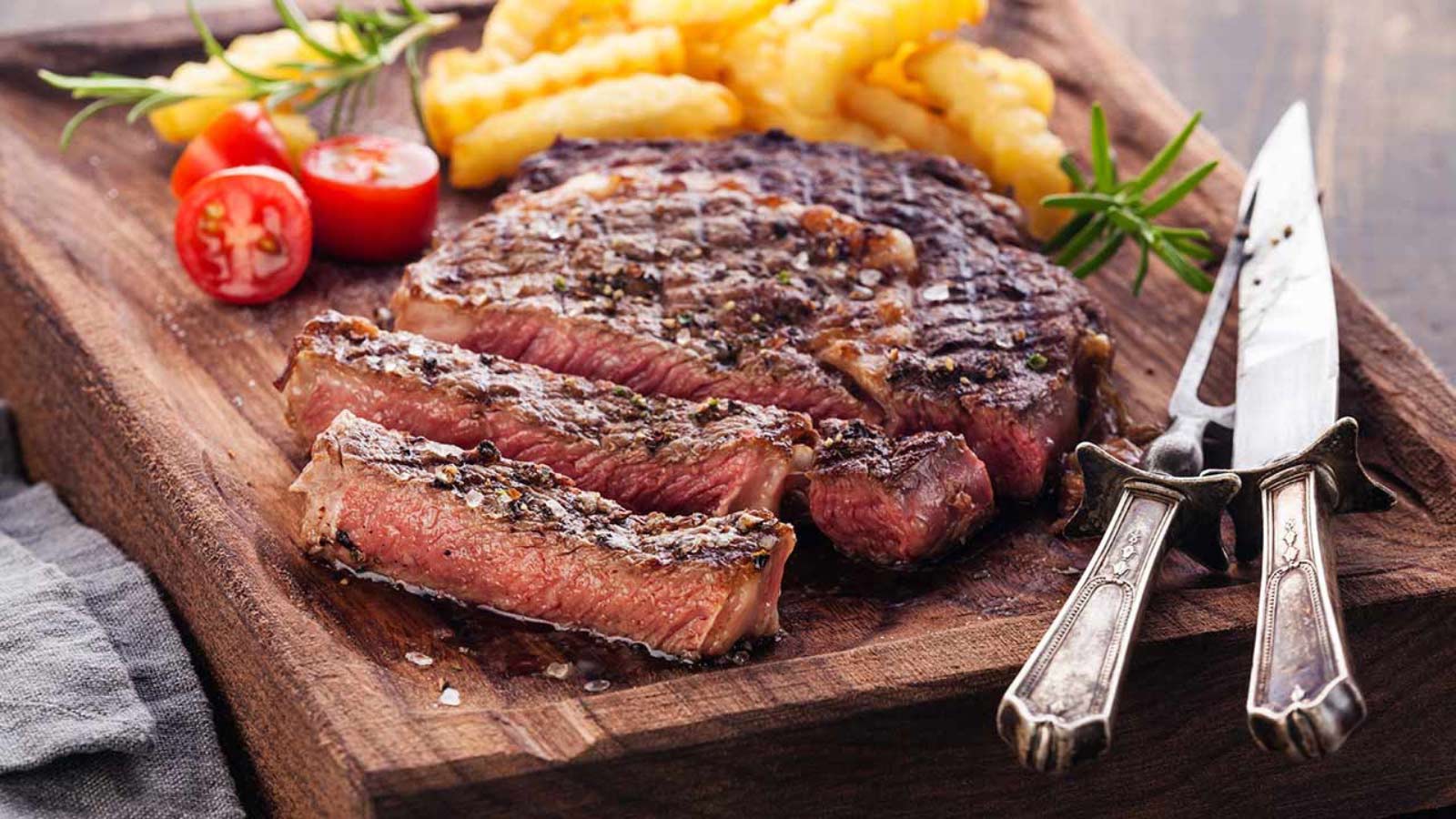 An air fryer ribeye steak, sliced on a cutting board.