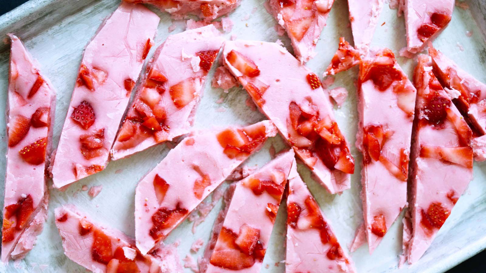 Pieces of Strawberry Frozen Yogurt Bark laying on a sheet pan.