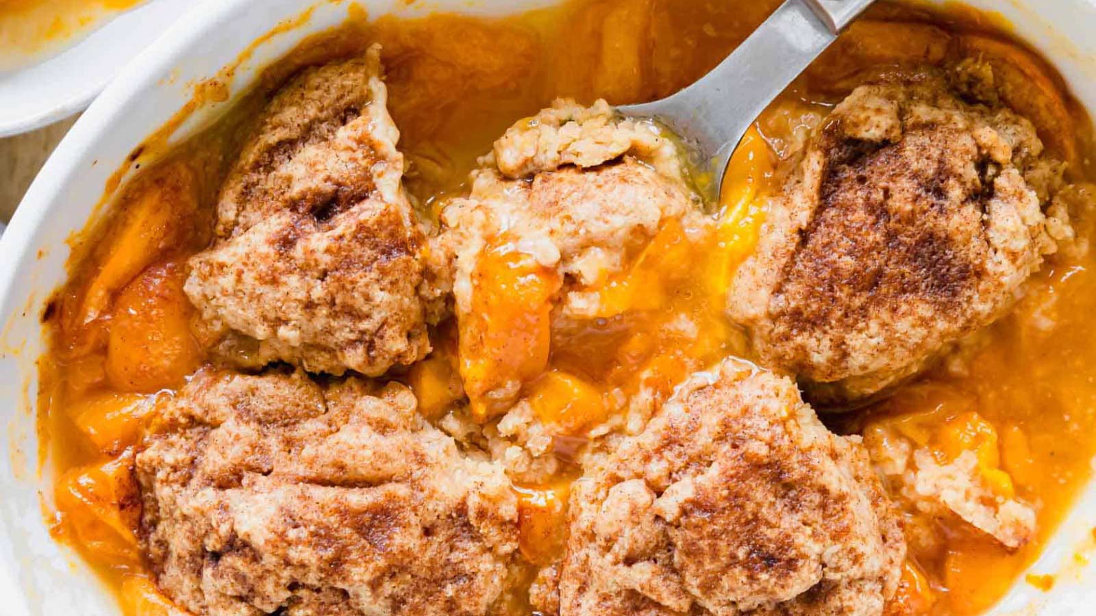 An overhead view of a white casserole dish filled with apricot cobbler,