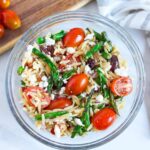 The mixed, finished, Asparagus Orzo salad with bacon in a glass bowl.