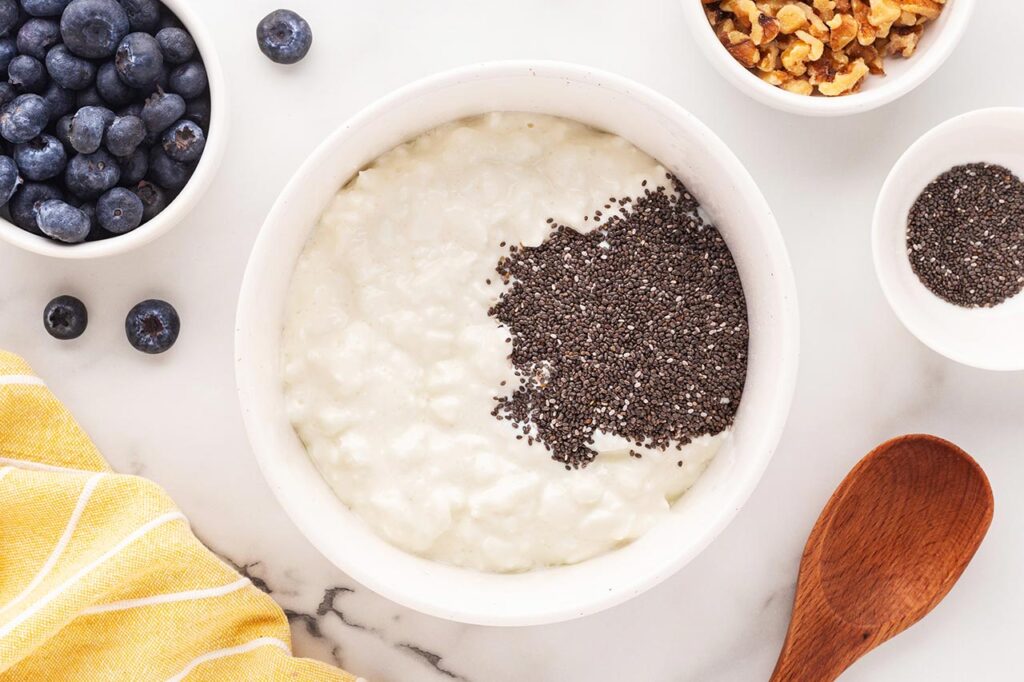 Chia seeds sprinkled over cottage cheese in a white bowl.