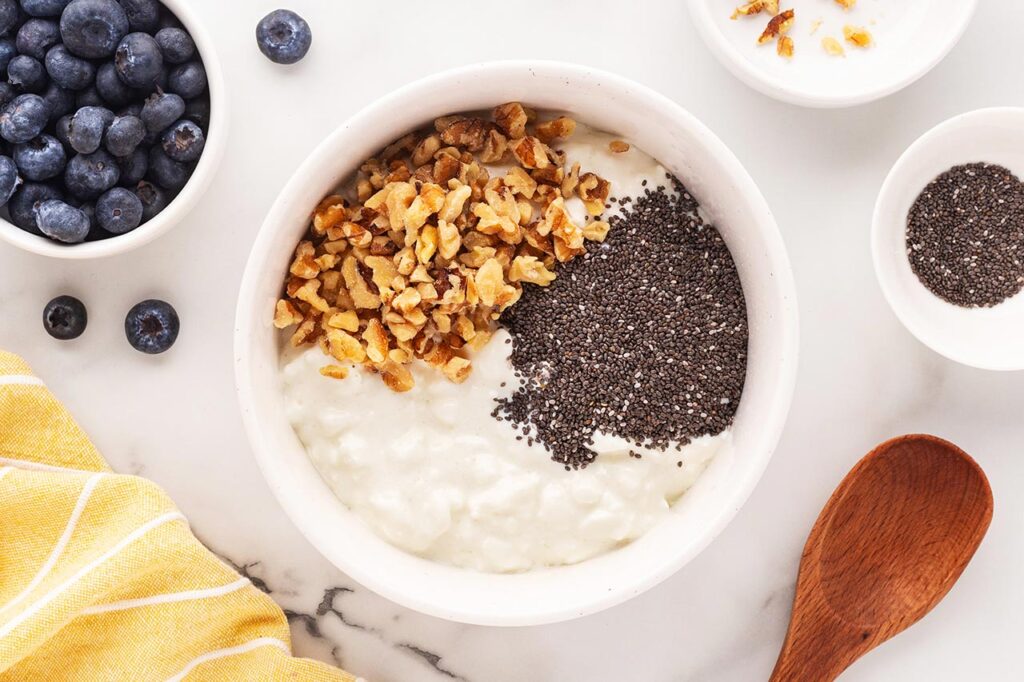 Walnuts sprinkled over cottage cheese in a white bowl.