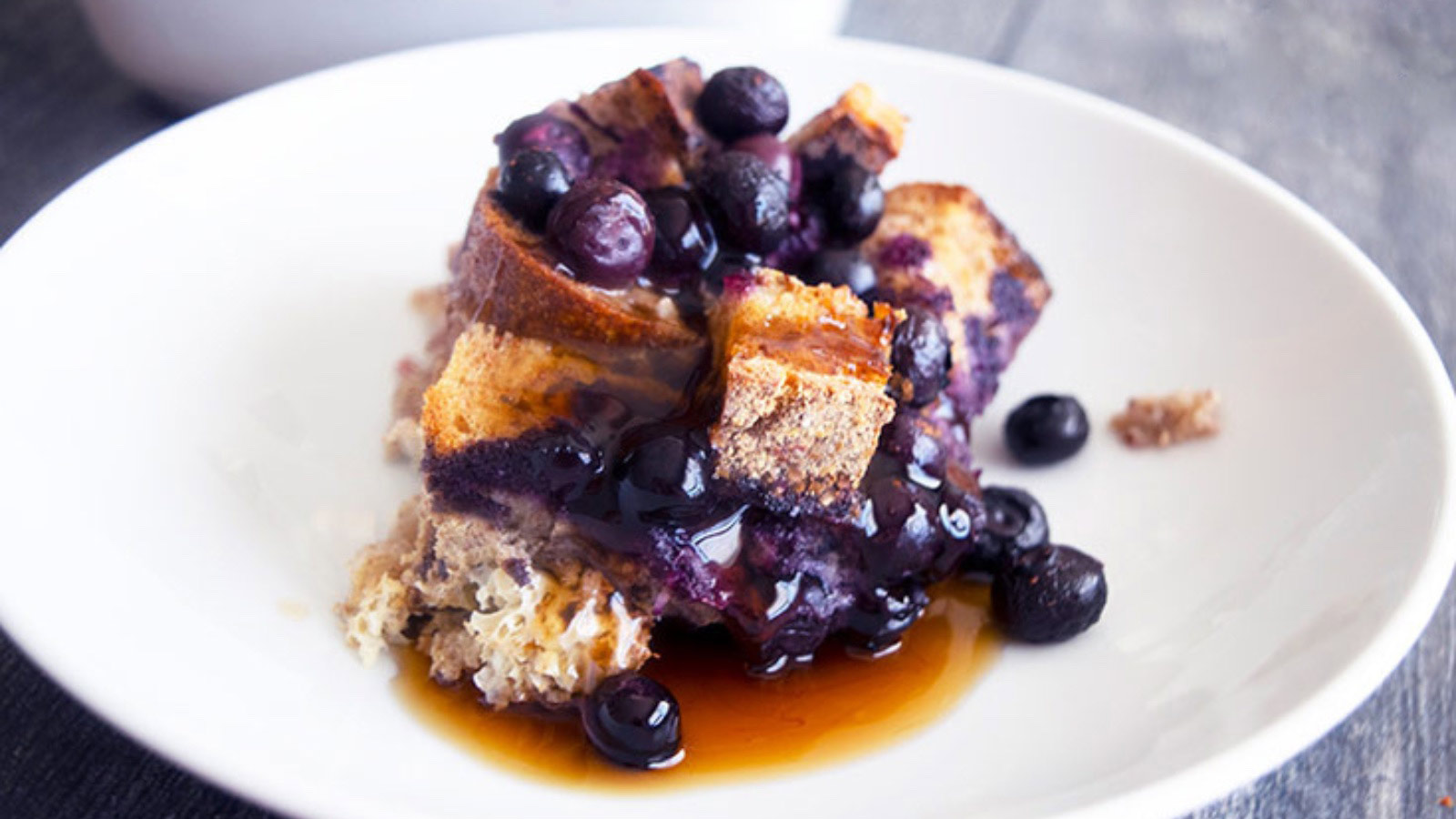 The finished Blueberry French Toast Casserole and a portion served on a plate.