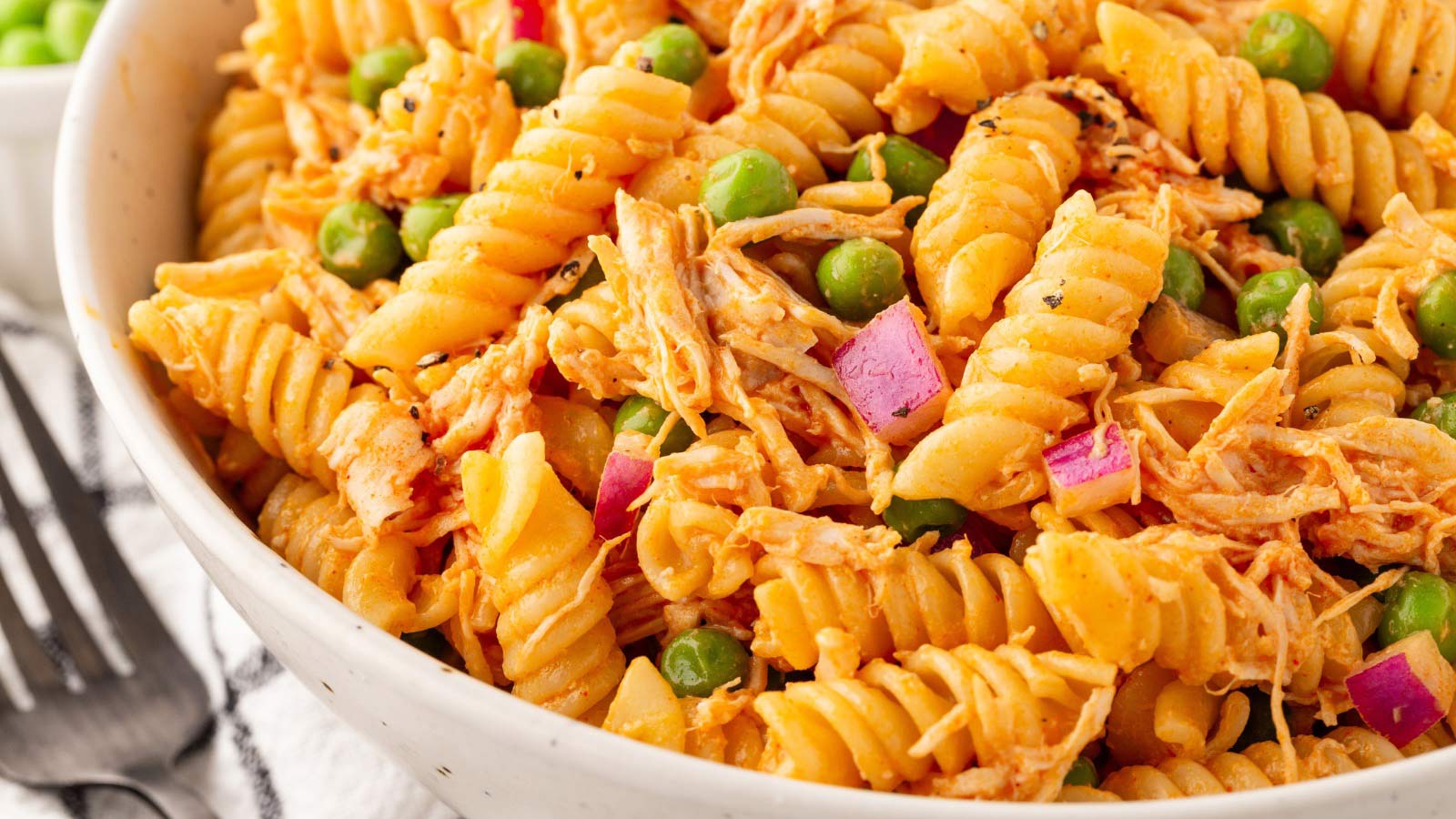 A closeup view of a white bowl filled with Buffalo Chicken Pasta Salad.