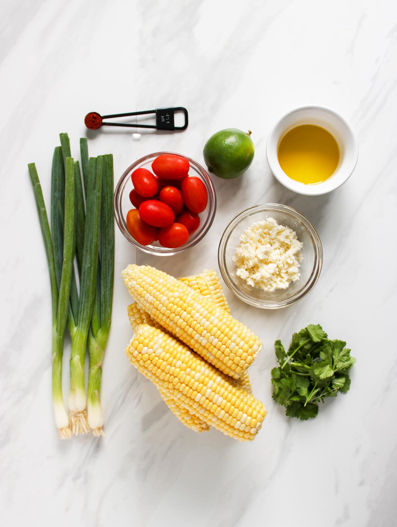 Ingredients for Roasted Corn Salad on a white marble surface.