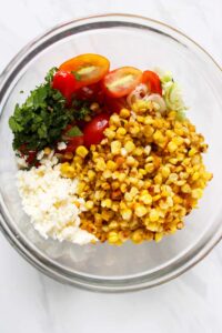 A mixing bowl with the Roasted Corn Salad Recipe ingredients in it.