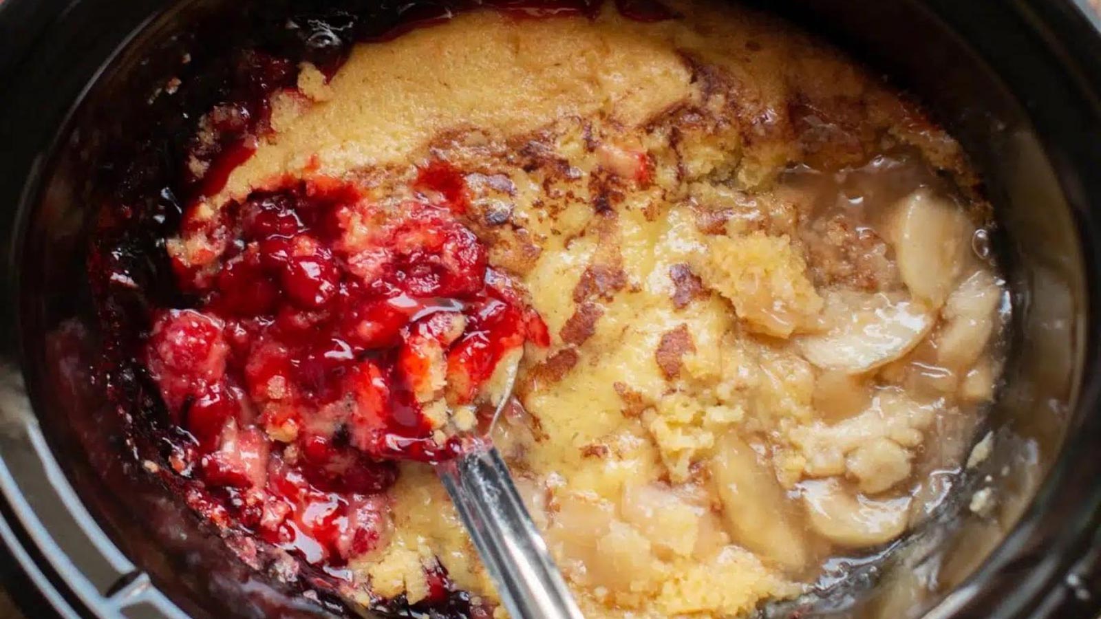 An overhead view of a slow cooker crock filled with a his and hers cobbler.