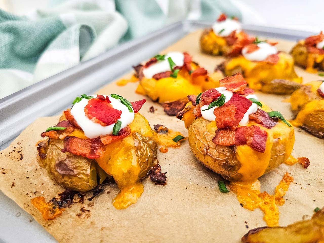 A side view of a sheet pan holding Loaded Smashed Potatoes.