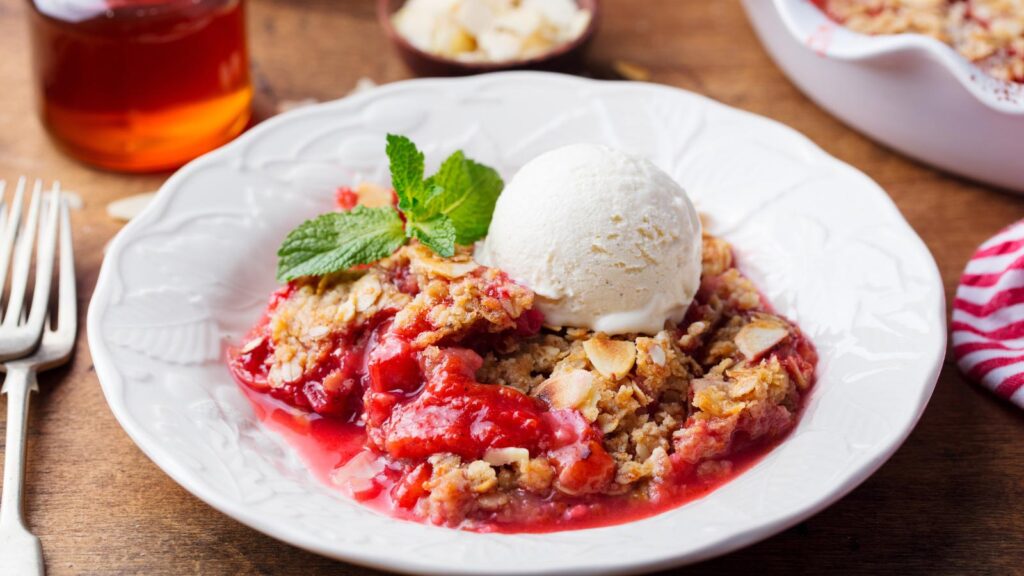 Raspberry cobbler with a scoop vanilla ice cream in a white bowl.