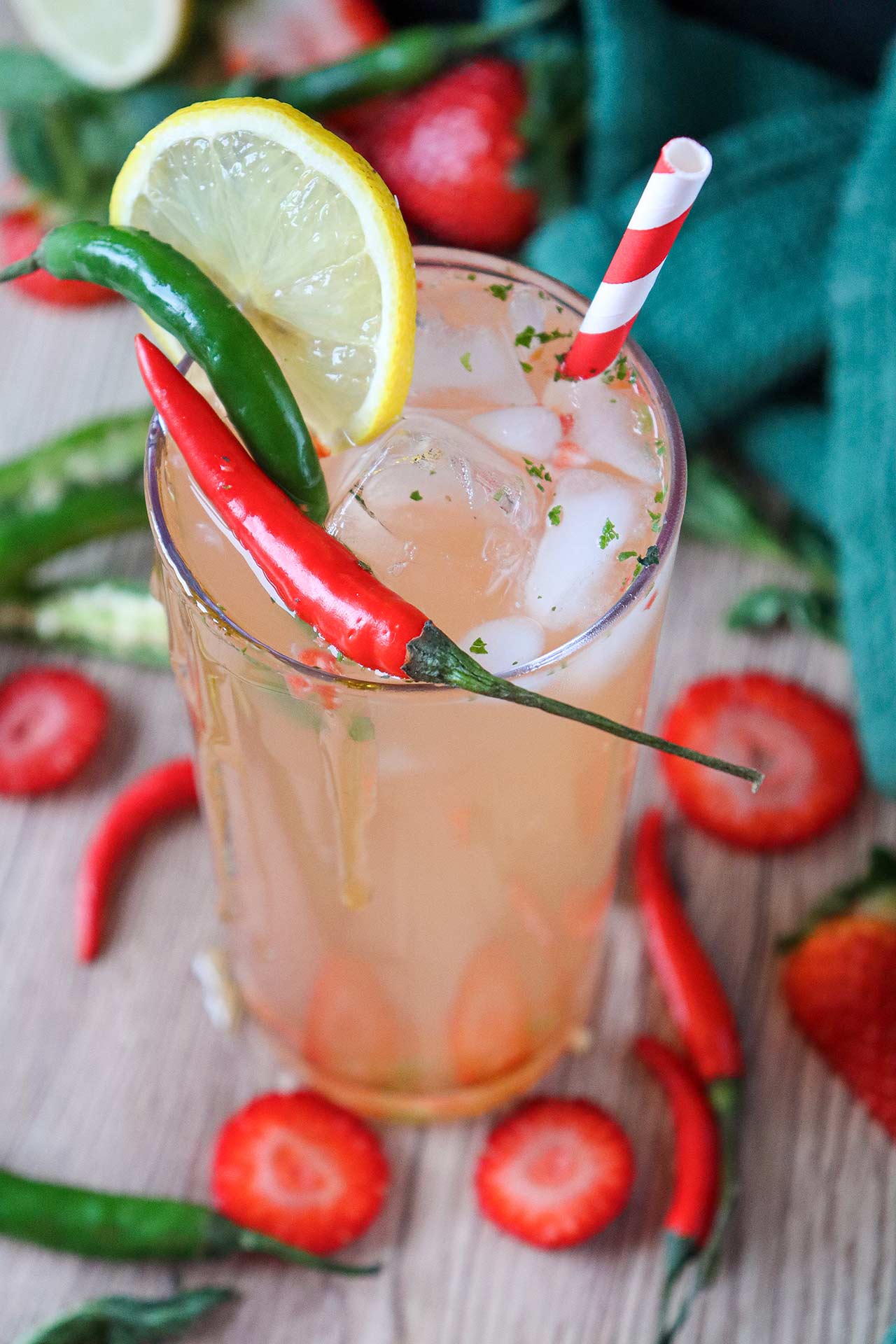 A semi-overhead view of a glass of strawberry mocktail garnished with peppers and a lime slice.
