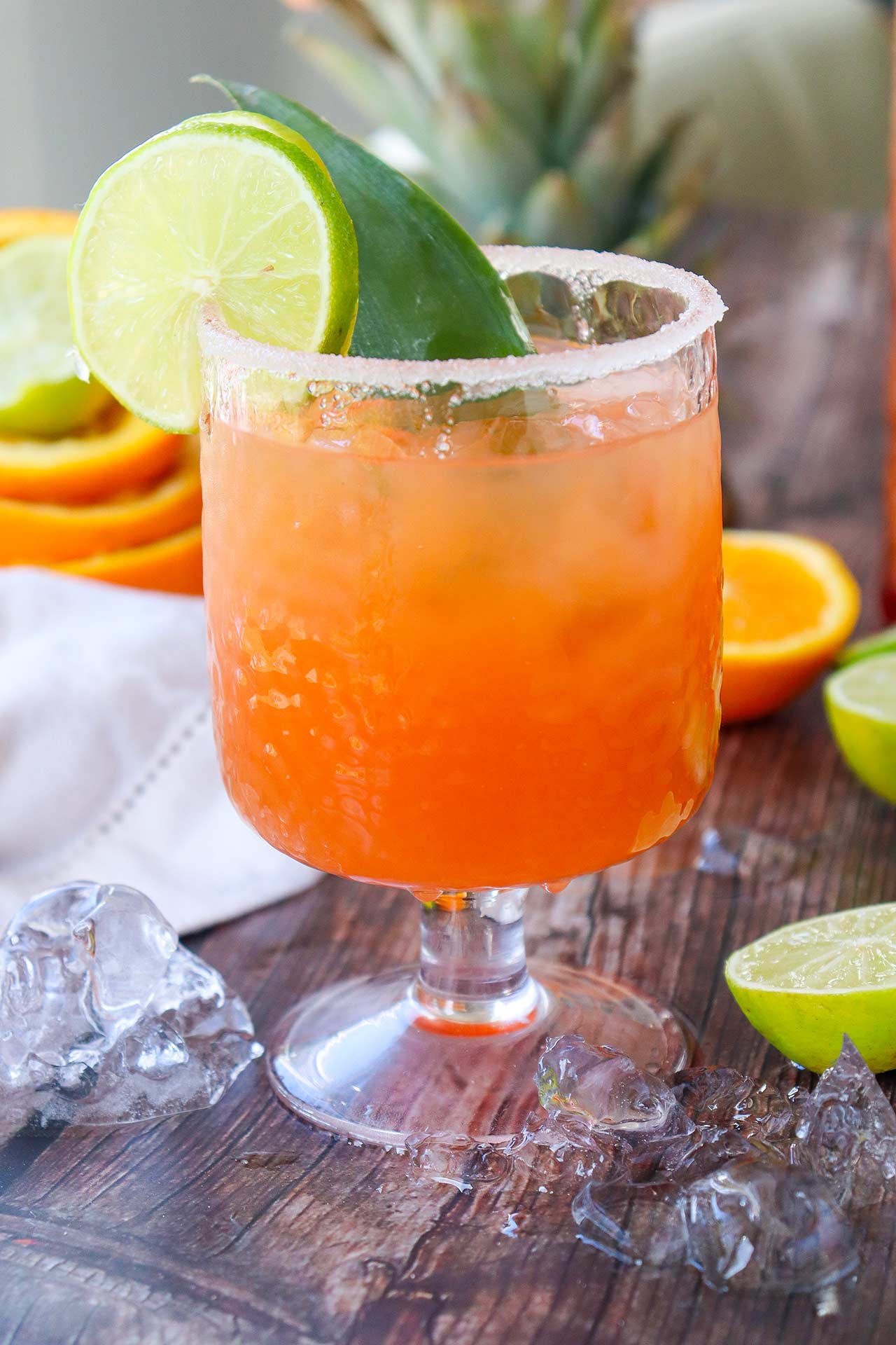 A side view of a glass of Tequila Sunrise Mocktail garnished with a lime slice.