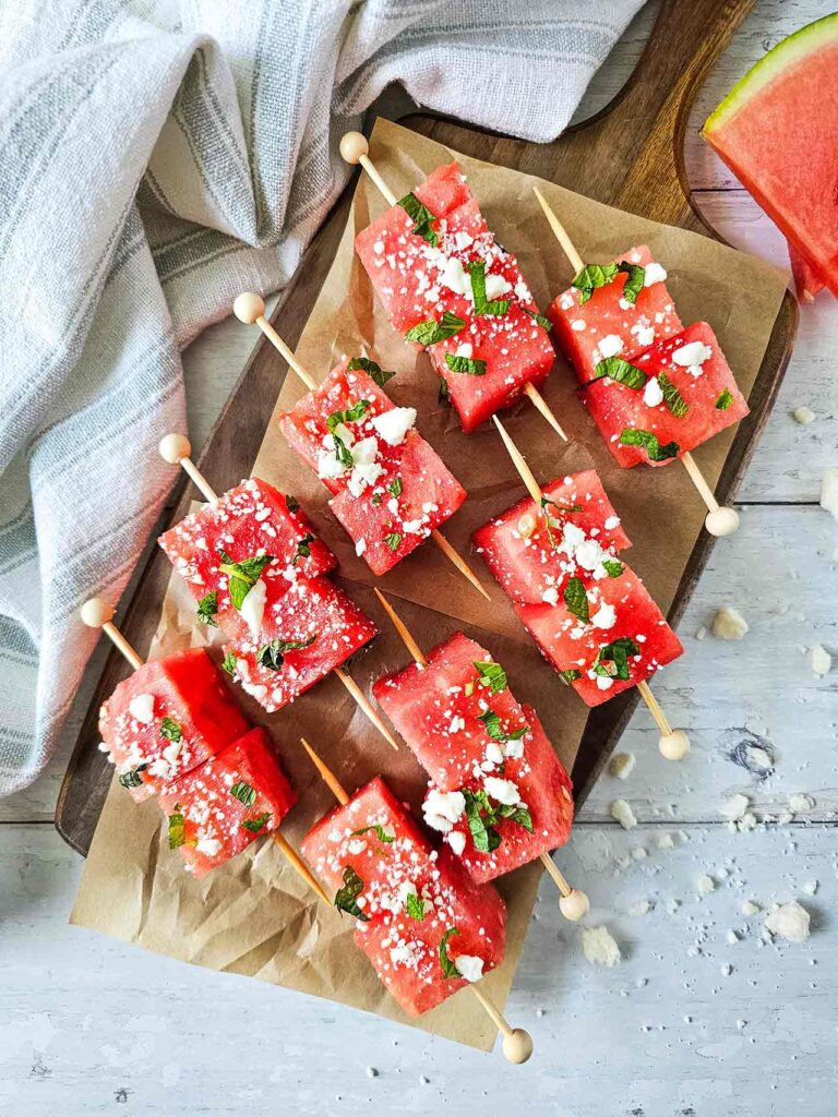 Watermelon Feta Skewers laying on a parchment lined cutting board.
