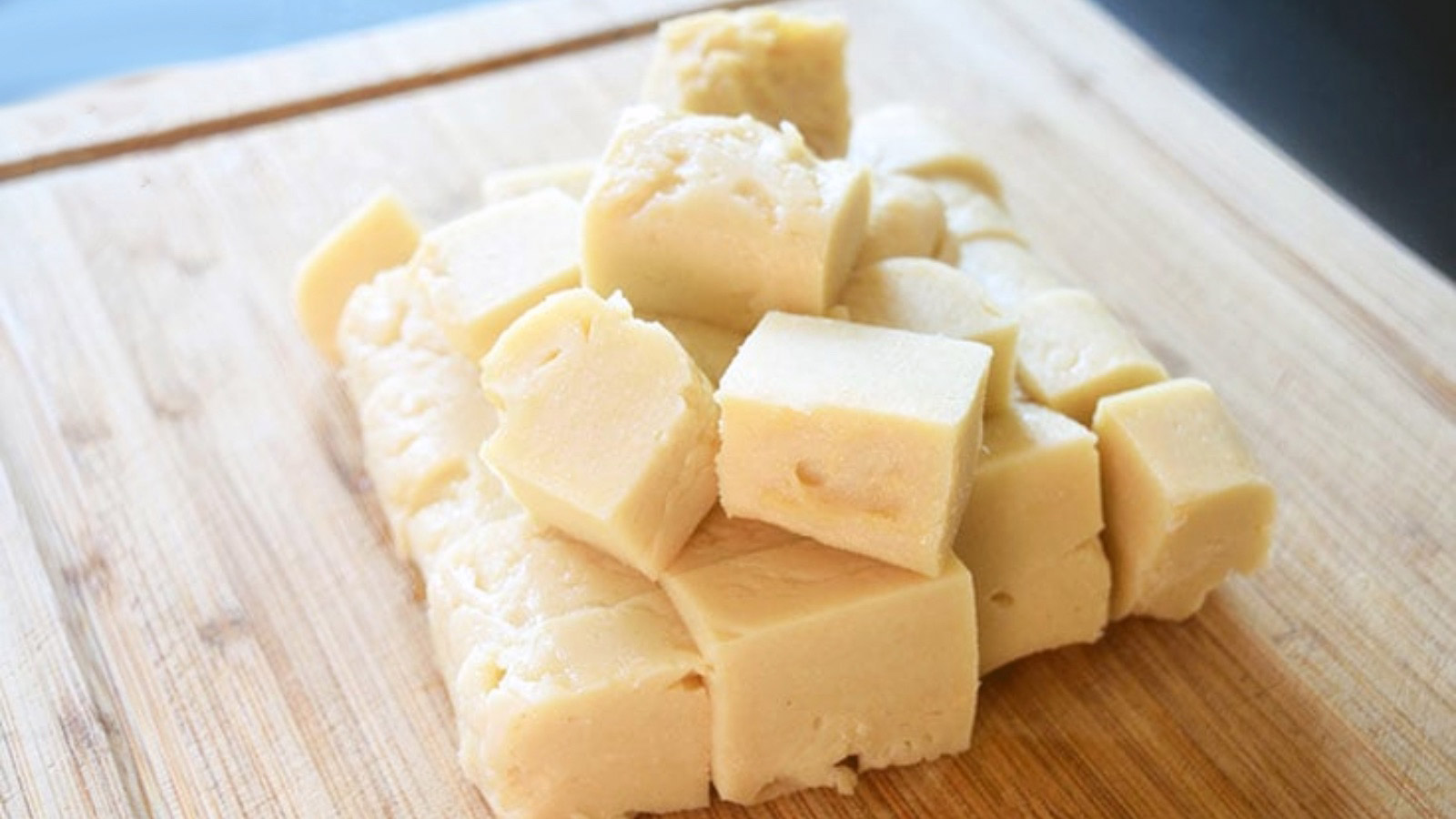 A pile of Chickpea Tofu cubes laying on a cutting board.