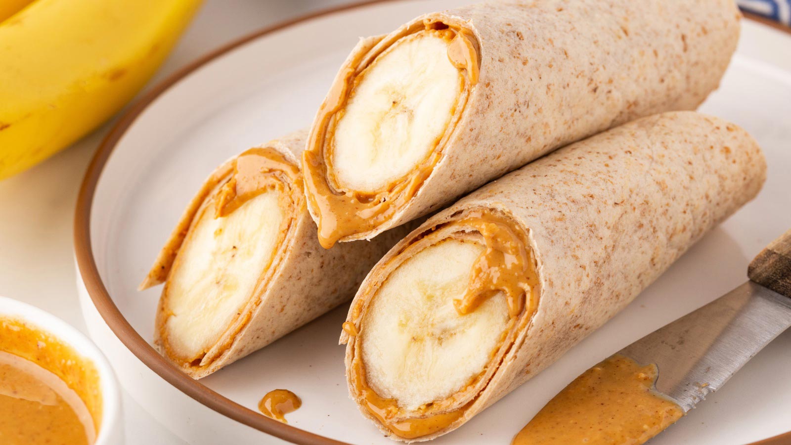 Three banana wraps stacked on a plate.