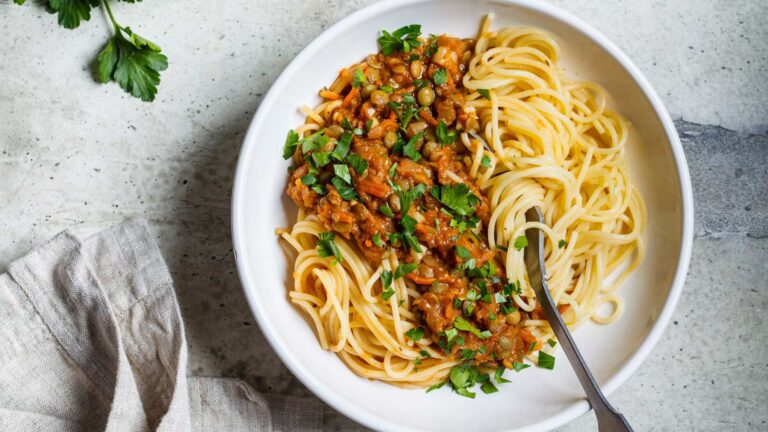 Vegetarian lentils bolognese pasta with parsley in a white dish. Healthy vegan food concept.