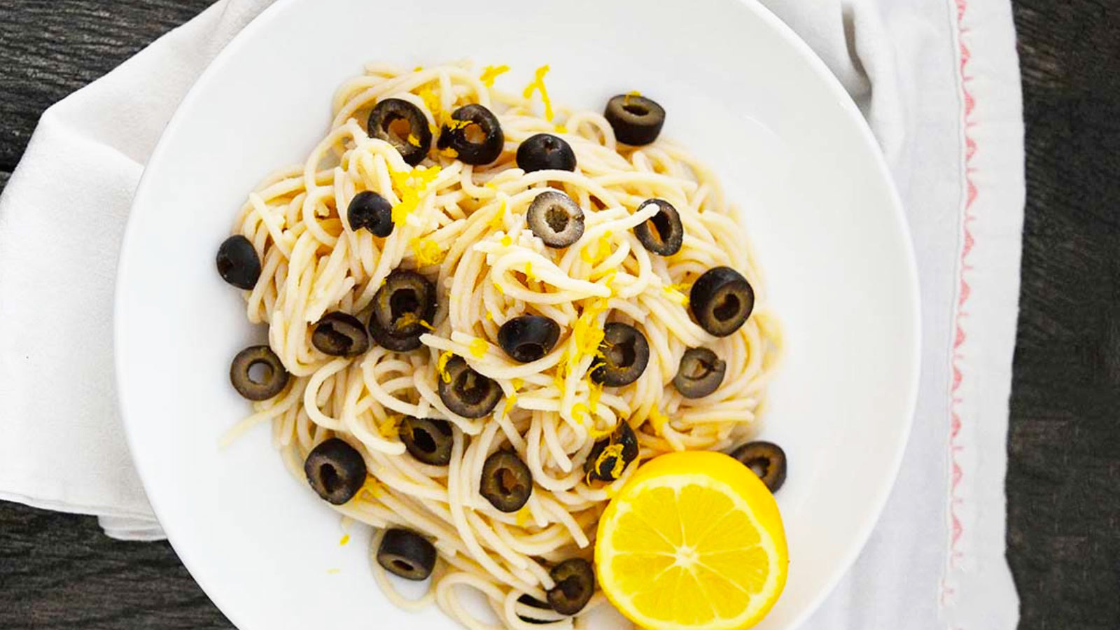 An overhead view of a white bowl filled with olive pasta.