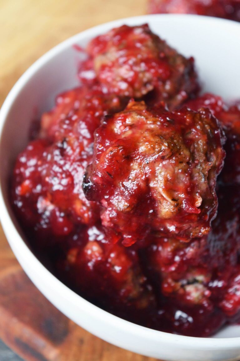 Overhead angled focus of white bowl filled with Cranberry Glazed Turkey Meatballs..