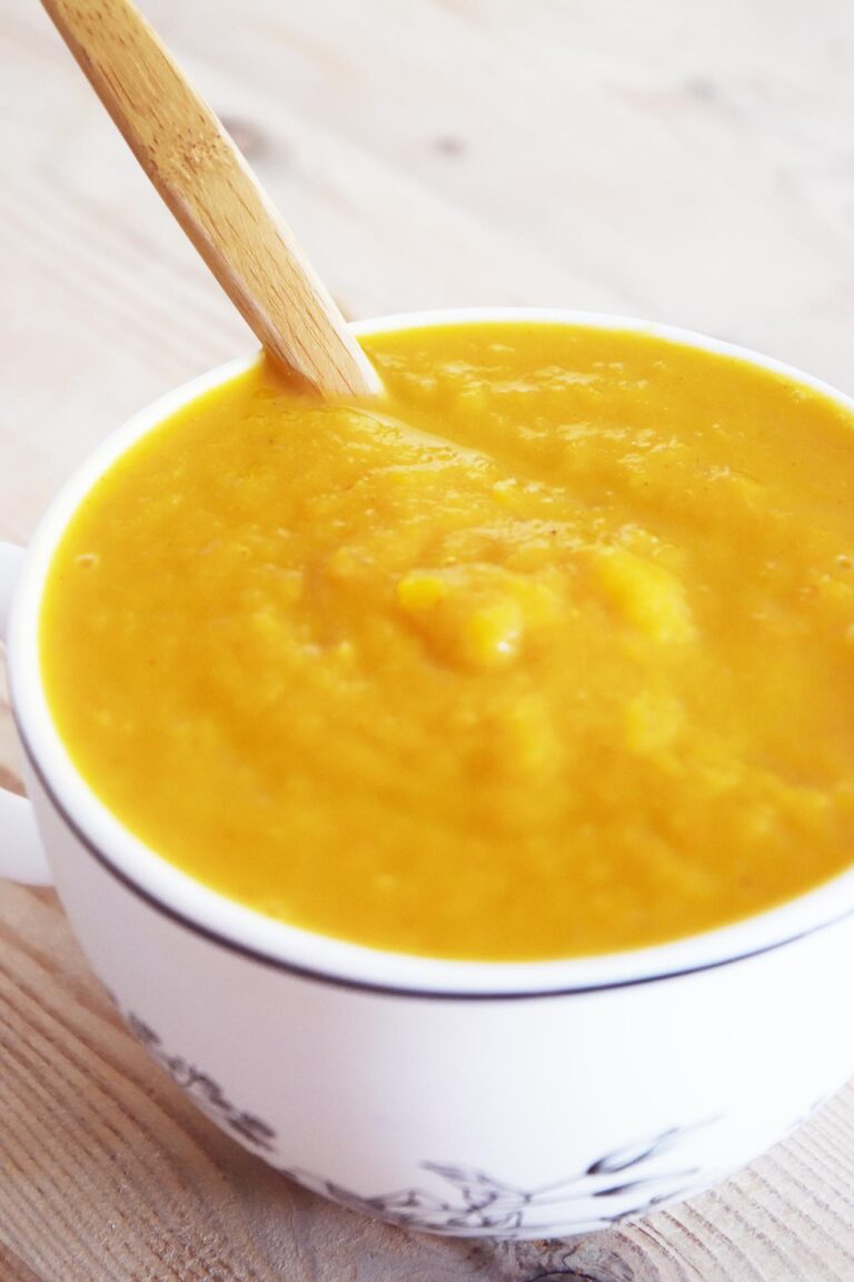 Butternut Squash Soup in a white mug with a wood spoon.