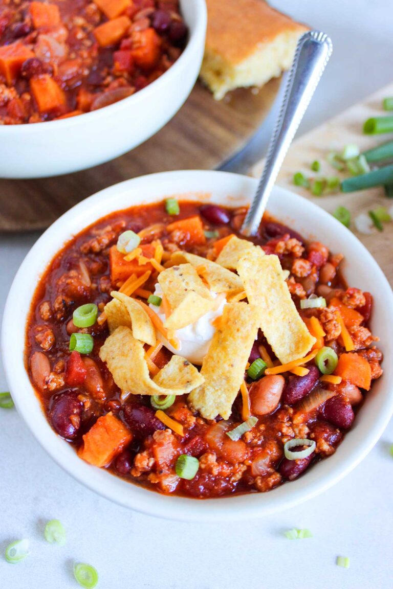 Front, partially-overhead view of a white bowl filled with Classic Chicken Chili.